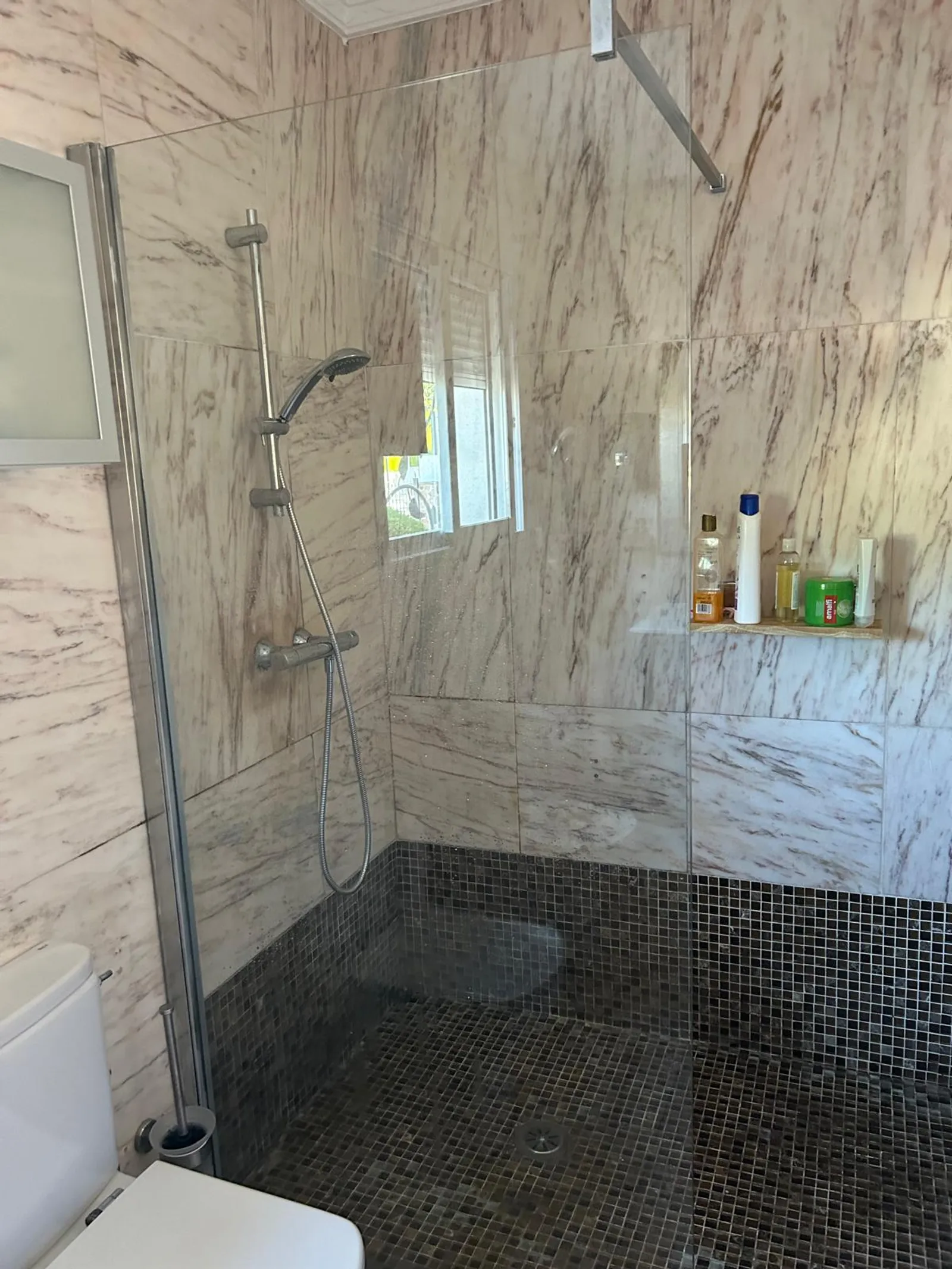 Ducha de obra a ras de suelo en el baño de mármol del chalet