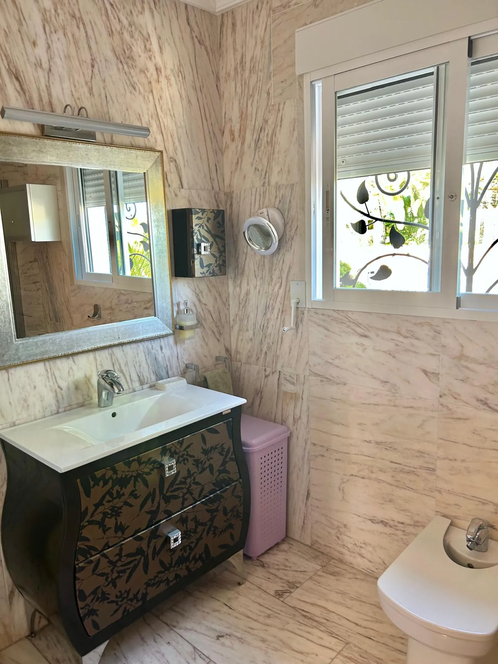 Baño principal revestido en mármol con lavabo sobre mueble
