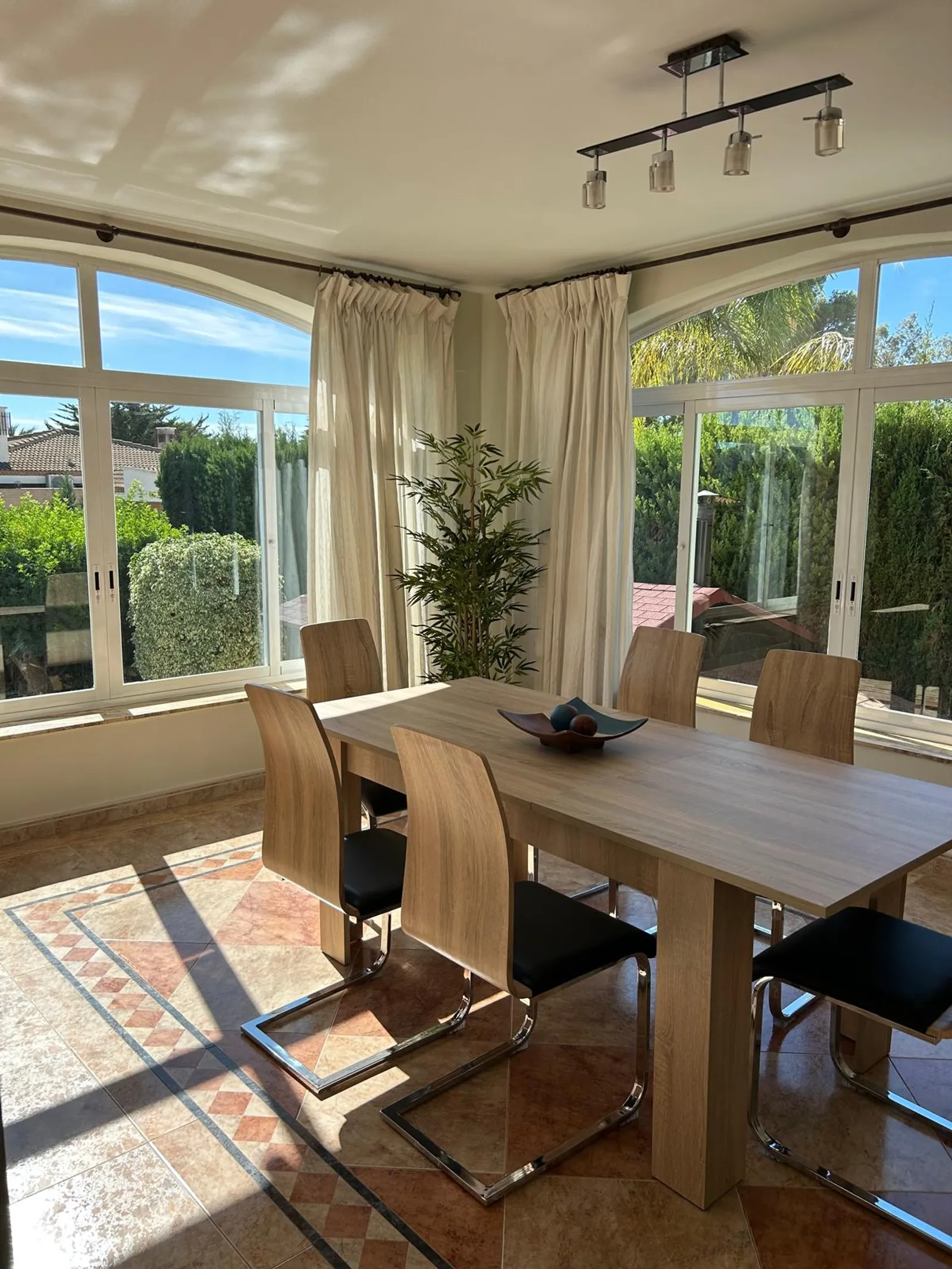 Comedor con ventanales de arco al jardín en el chalet de Benidorm