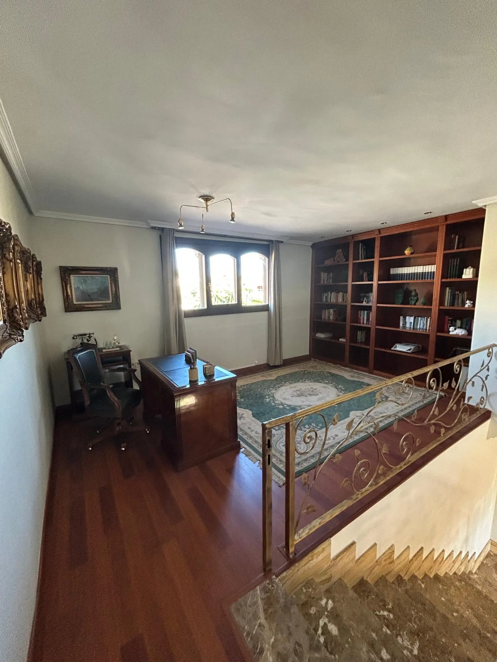 Despacho con biblioteca de madera sobre el hueco de escalera