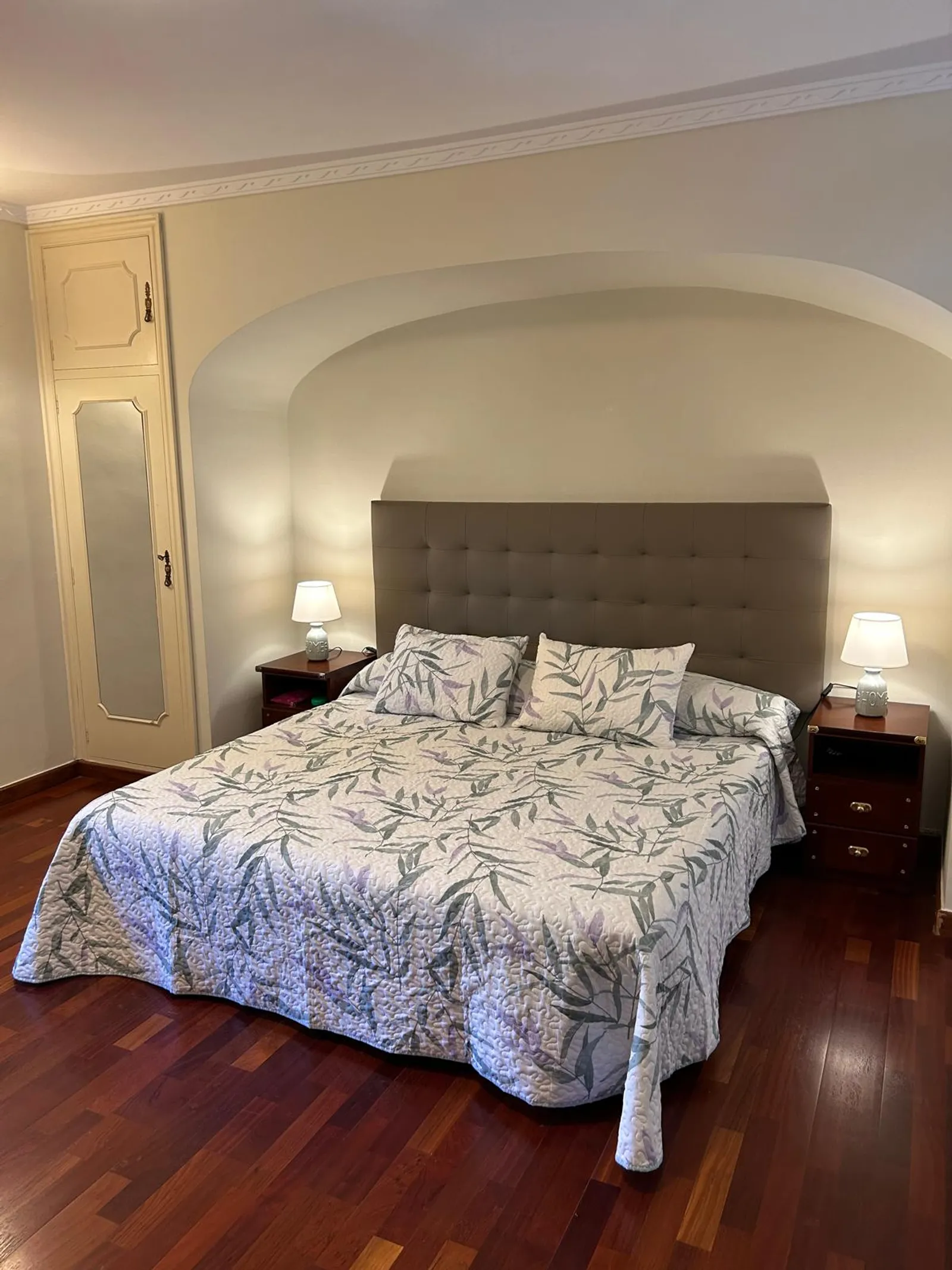 Dormitorio principal con cabecero tapizado y suelo de madera