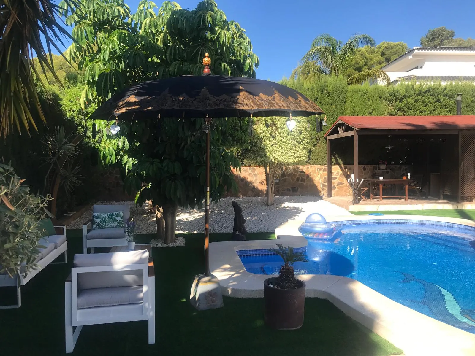 Piscina privada y zona chill-out bajo sombrilla en el chalet de Benidorm