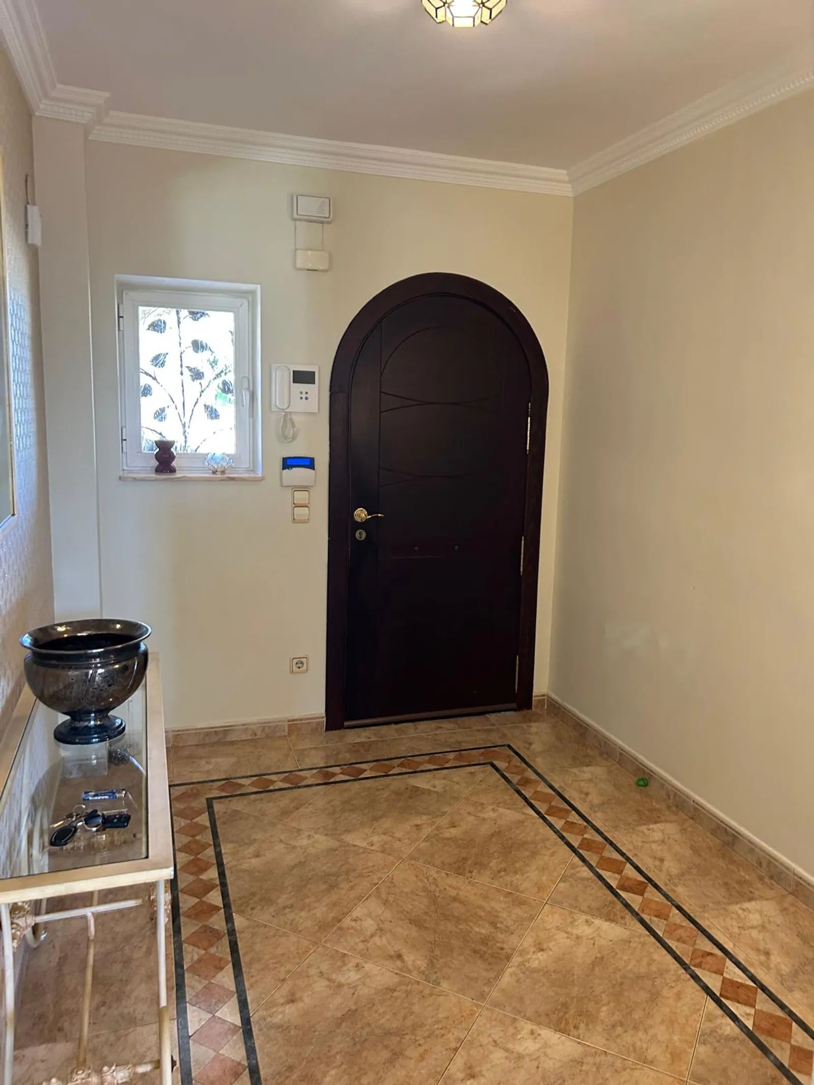 Recibidor con puerta de arco y suelo de mármol del chalet en Benidorm