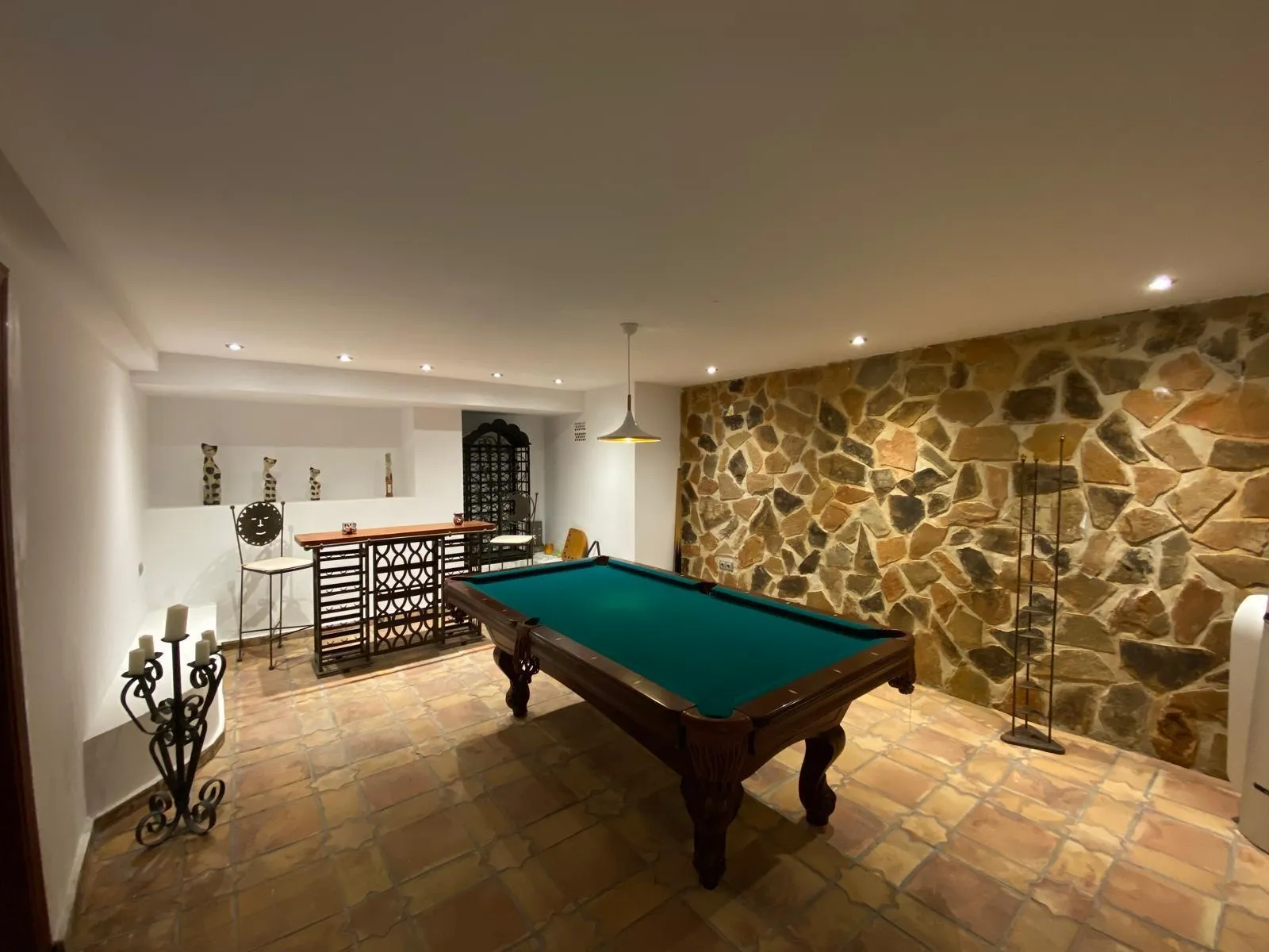 Sala de billar con pared de piedra y bodega en el chalet de Benidorm