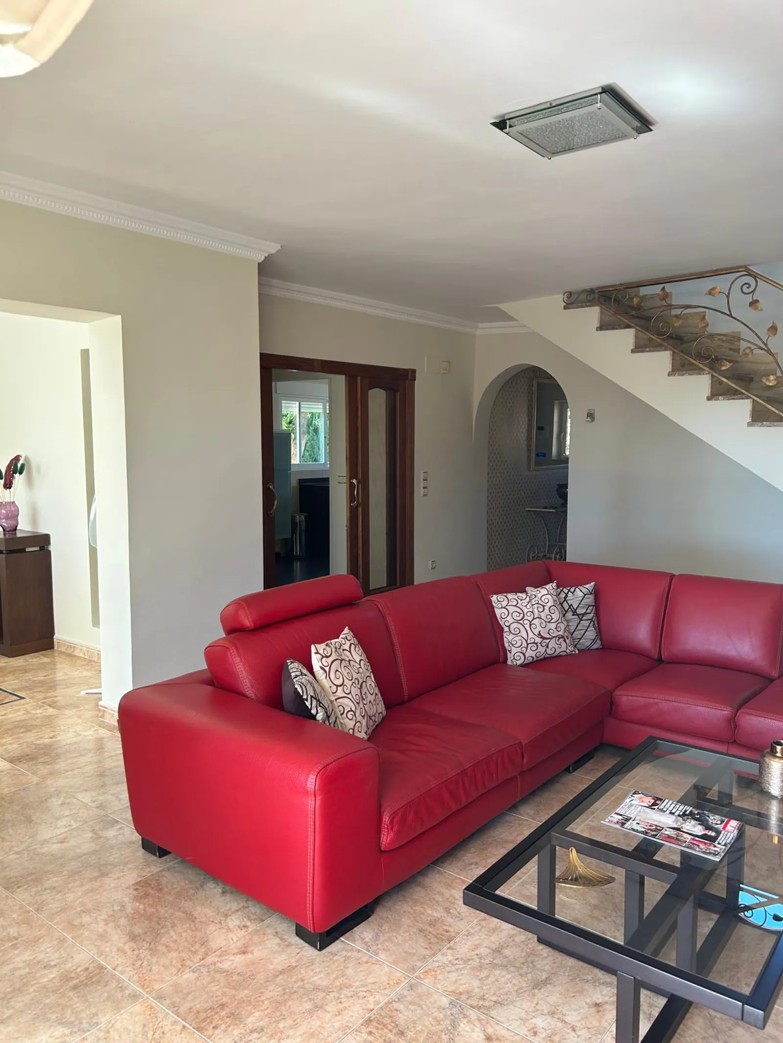 Salón principal con sofá rincón y escalera de forja, chalet en Benidorm