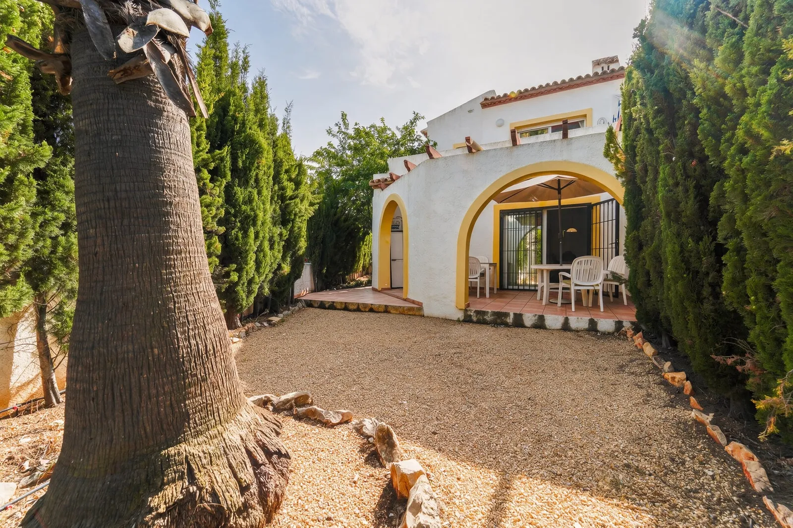 Fachada de la casa en venta en Calpe con jardín de grava y porche de arcos